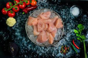 dice chicken breast in a bowl filled with ice on a bed of ice