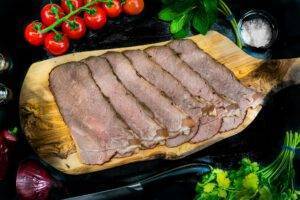 slices of roast beef on a wooden chopping board