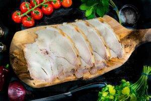 slices of traditional roast pork on a wooden chopping board