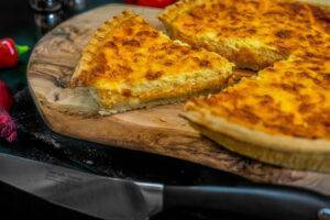 cheese and onion quiche on a wooden chopping board