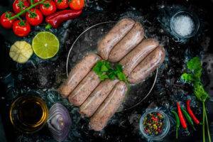 Cumberland sausages on a bed of ice surrounded by onion and garnishes