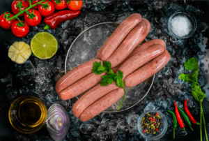 beef and pork sausages on ice surrounded by garlic and garnishes