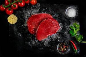 2 cuts of steak fillet on a bed of ice surrounded by ice and garnish
