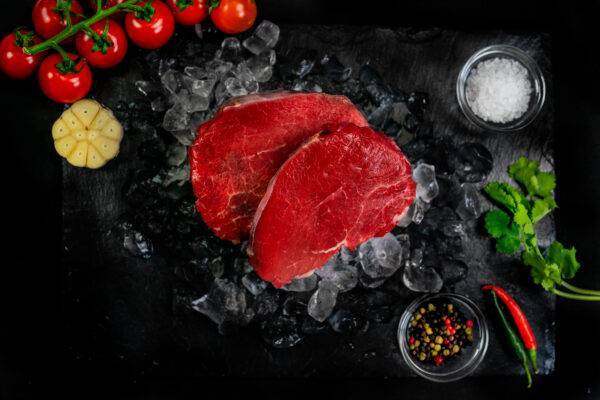 2 cuts of steak fillet on a bed of ice surrounded by ice and garnish