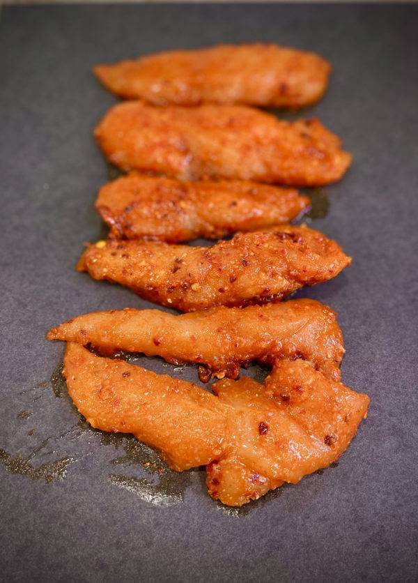 Marinated Chicken Strips on a grey surface