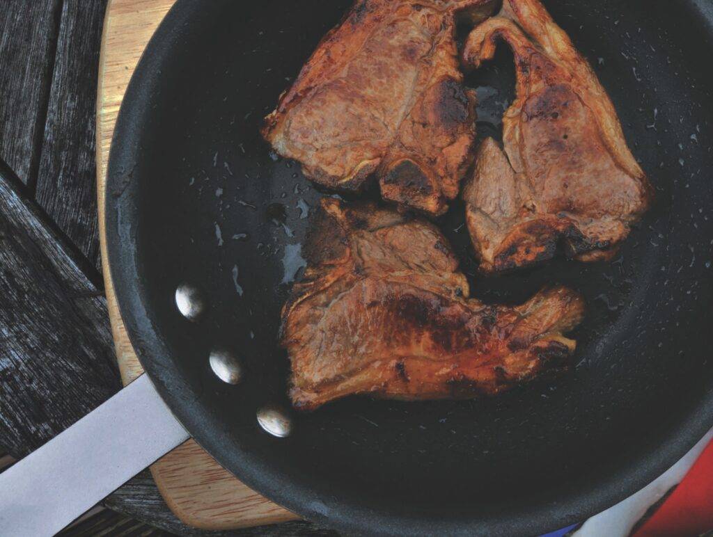 Three lamb chops in a black pan