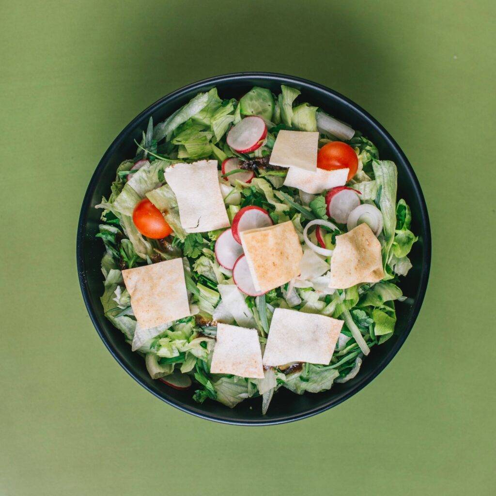 Salad in a black bowl on a green surface